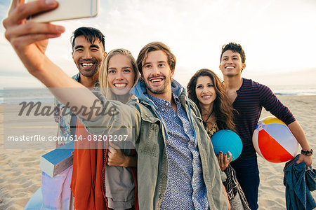 Group of friends on beach, taking self portrait with smartphone