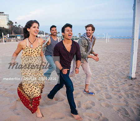 Group of friends walking along beach, laughing
