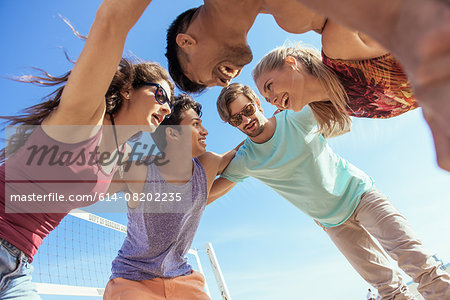 Group of friends in huddle on beach, low angle view