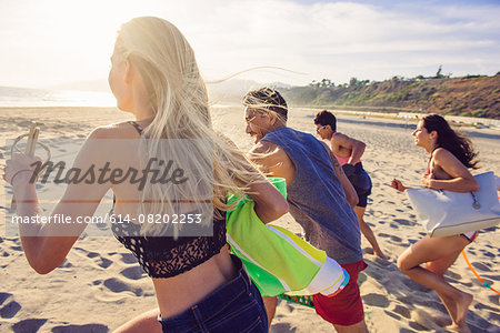 Group of friends running on beach, rear view