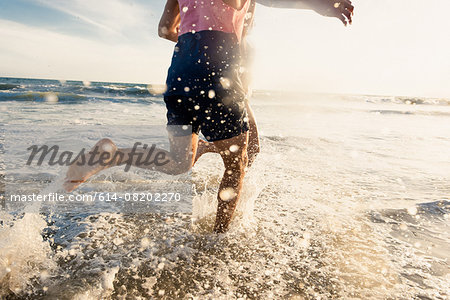 Young man running in sea, low section