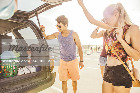 Group of friends standing by car, at beach