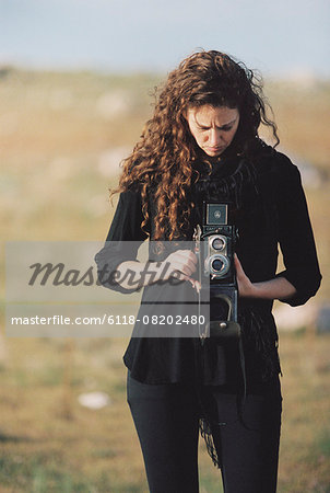 A woman taking a picture with an old fashioned medium format camera.