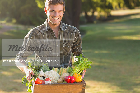 Smiling man carrying box of vegetables