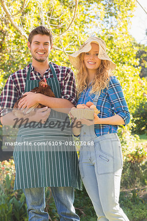 Happy farmers holding chicken and eggs