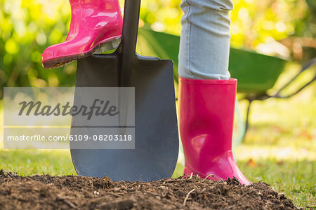 Woman wearing pink rubber boots using shovel