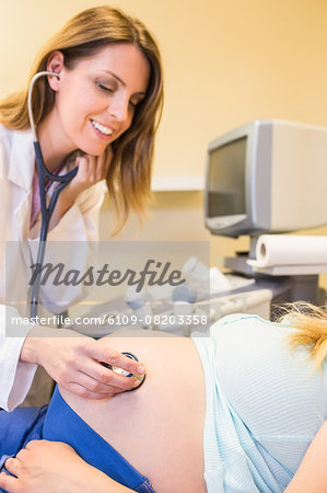 Doctor listening to pregnant patients belly
