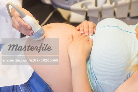 Doctor scanning pregnant patient's belly