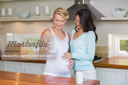 Woman touching her pregnant girlfriend stomach