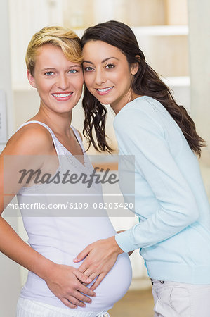 Lesbian girl touching her pregnant girlfriends stomach