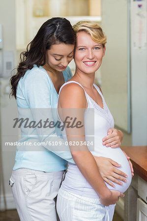 Lesbian girl touching her pregnant girlfriends stomach