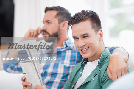Homosexual couple men reading the newspaper and on the phone