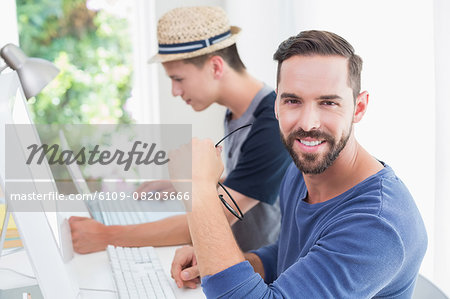 Happy handsome man looking at camera with his colleagues behind