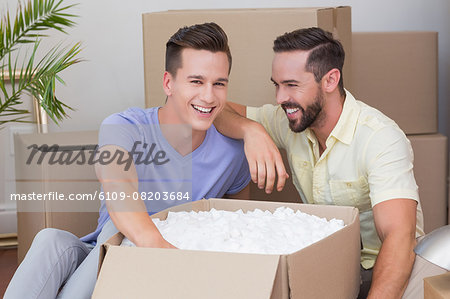 Happy homosexual couple unpacking box