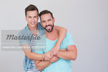 Happy homosexual couple looking at camera and hugging