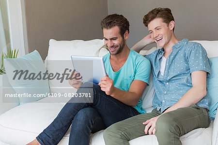 Cute homosexual couple looking at tablet on couch