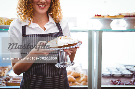 Happy pretty barista holding plate with cake