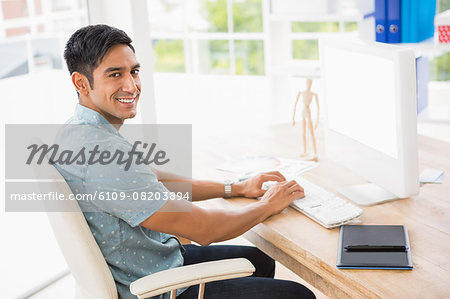 Portrait of smiling casual businessman working with computer and looking at camera