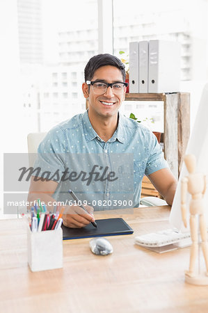 Portrait of smiling casual businessman working with digitizer and looking at camera