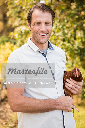 Happy farmer holding chicken