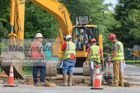 Construction workers digging hole to replace watermain