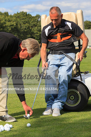 Instructor placing golf ball for man with a spinal cord injury