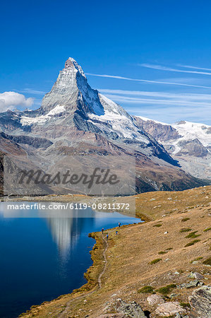 Hikers walking on the path beside the Stellisee with the Matterhorn reflected, Zermatt, Canton of Valais, Pennine Alps, Swiss Alps, Switzerland, Europe