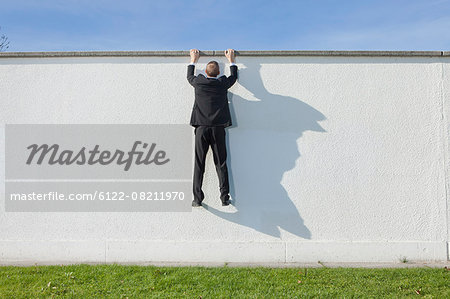 Businessman climbing over wall