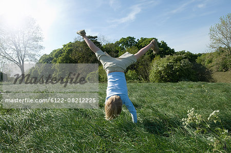 Boy doing handstand in field