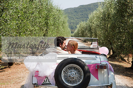 Newlyweds kissing in classic car