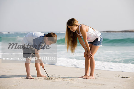 Girl and boy drawing pictures in the sand