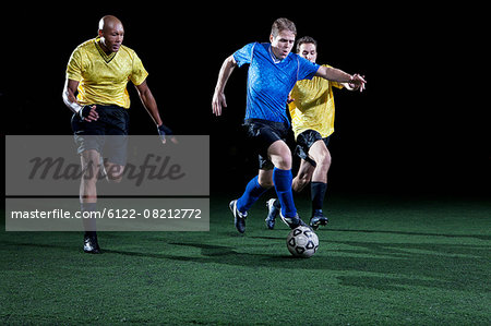 Soccer players tackling on pitch