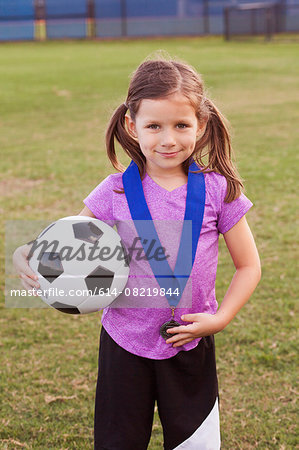 Portrait of girl football player with medal on practice pitch