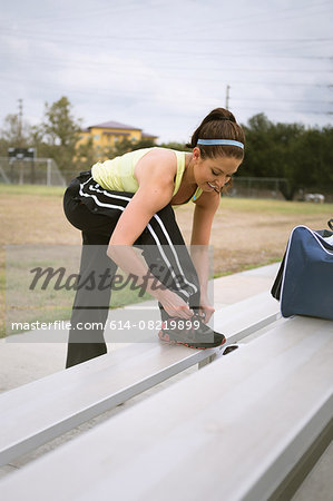 Soccer player tying shoe lace on bench
