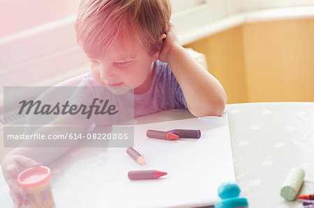 High angle view of boy sitting at table with art supplies