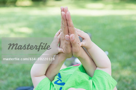Cropped shot of mothers and baby sons hands together in park