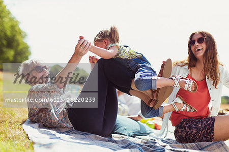 Playful grandmother and granddaughter on blanket in sunny field