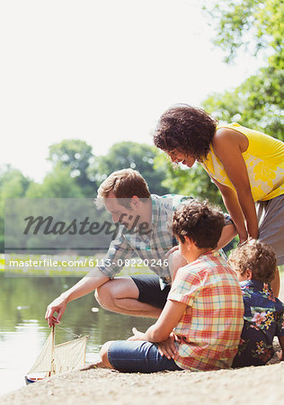 Family playing with toy sailboat at lakeside