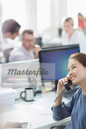 Smiling businesswoman talking on telephone at desk in office