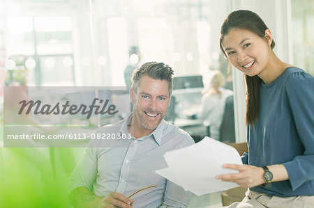 Portrait smiling business people reviewing paperwork in office