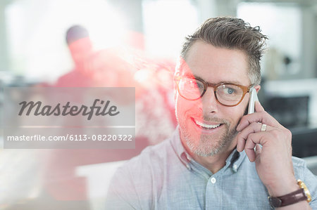 Smiling businessman talking on cell phone in office