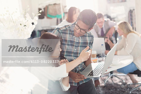 Fashion designers brainstorming with laptop in office Fashion designers brainstorming with laptop in office