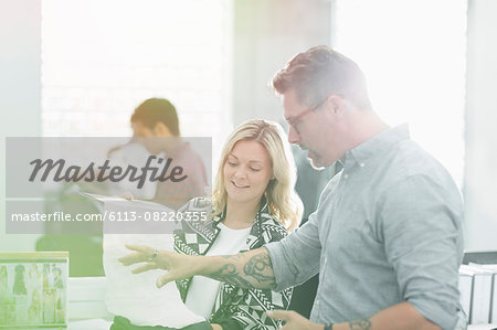 Fashion designers discussing fabric swatch in sunny office