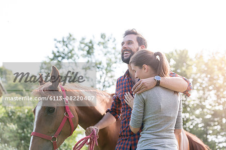 Smiling couple hugging near horse