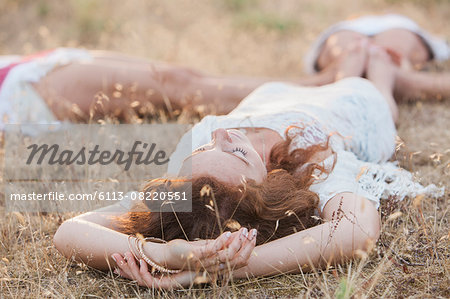 Boho women laying in circle with feet touching in rural field