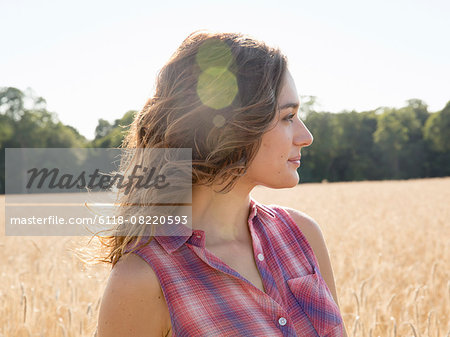 A young woman standing in a field of tall ripe corn.