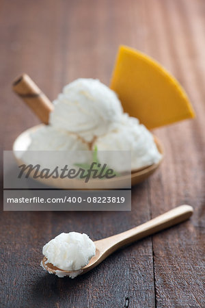 Scoop vanilla ice cream with waffle on wood background. Focus on front spoon.