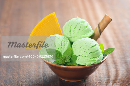 Scoop of mint ice cream in bowl on rustic old wooden vintage background.