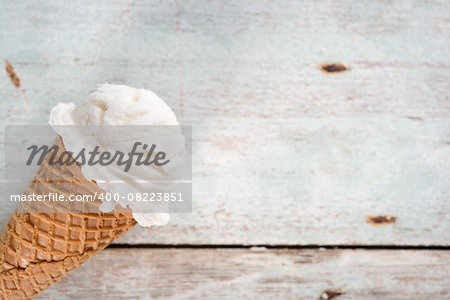 Single vanilla ice cream in a waffle cones over wooden background.