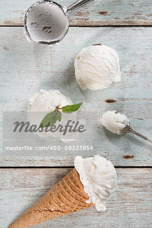 Top view vanilla ice cream in waffle cone with utensil on wood background.